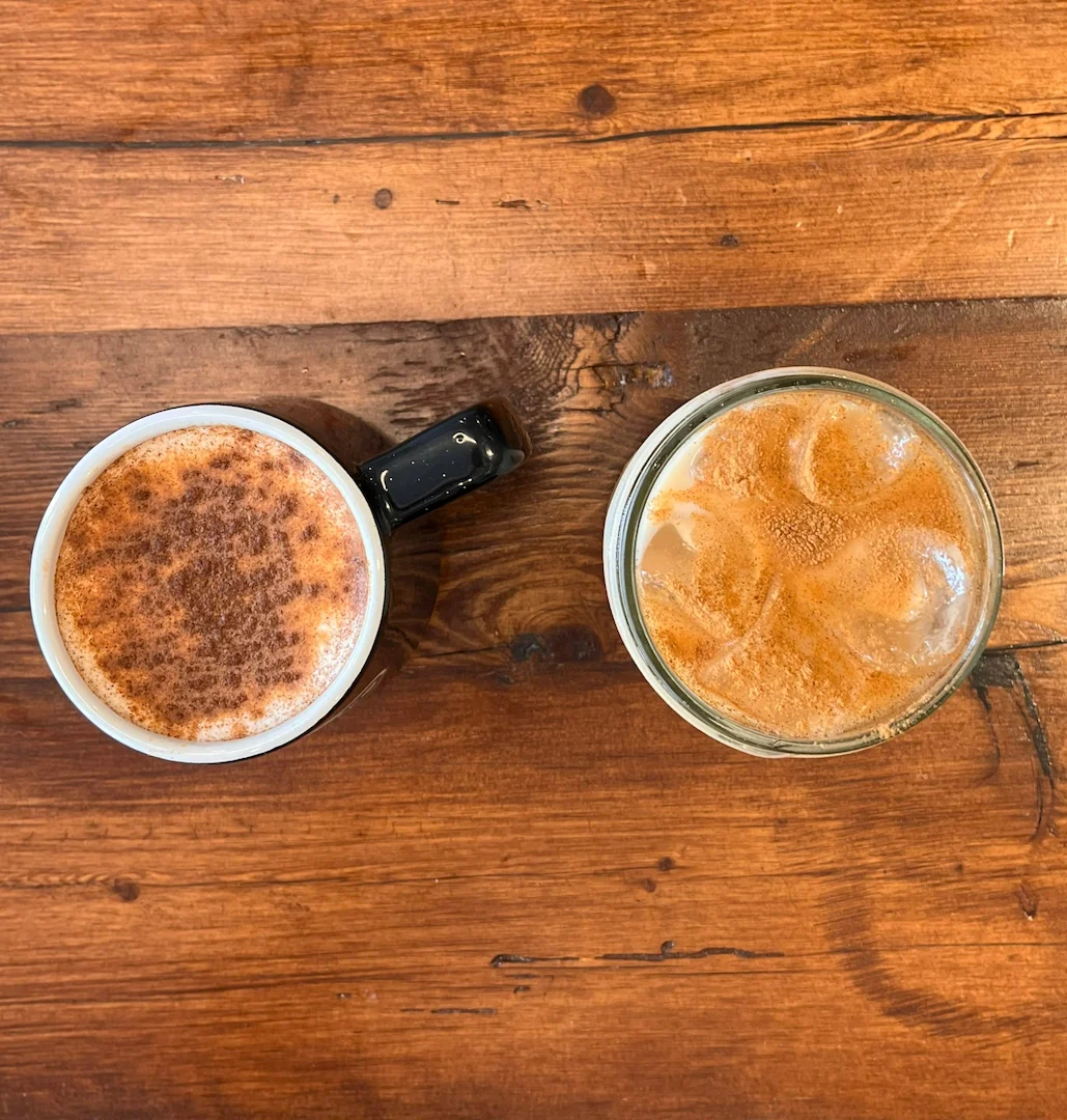 A hot latte and an iced coffee from above on a wood table