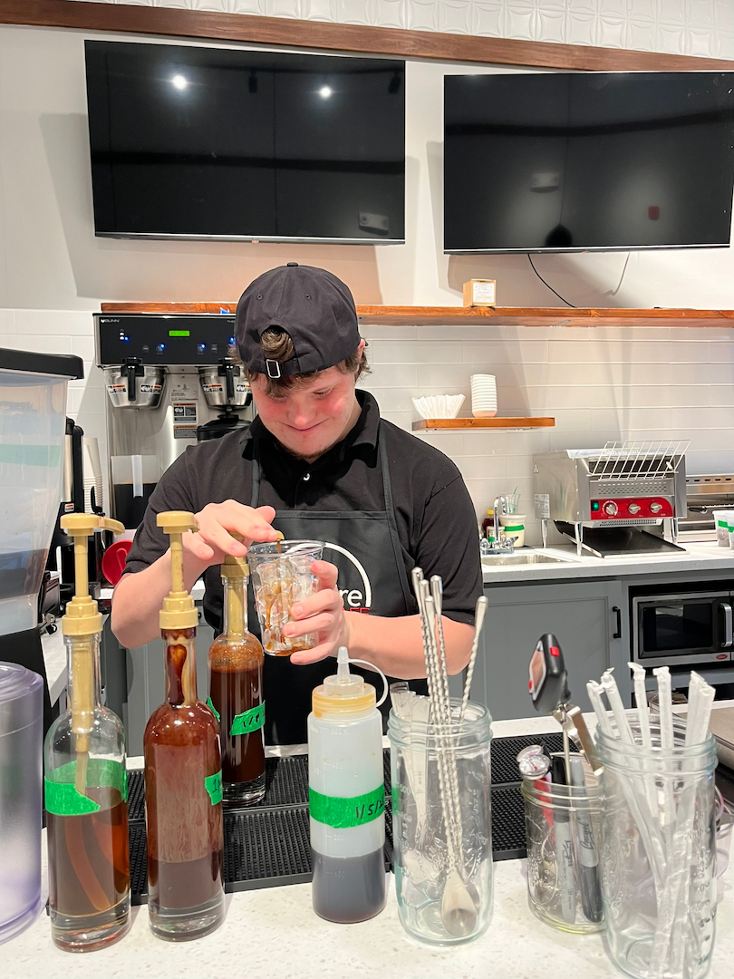 An INspire Cafe team member mixing a specialty latte at the syrup station