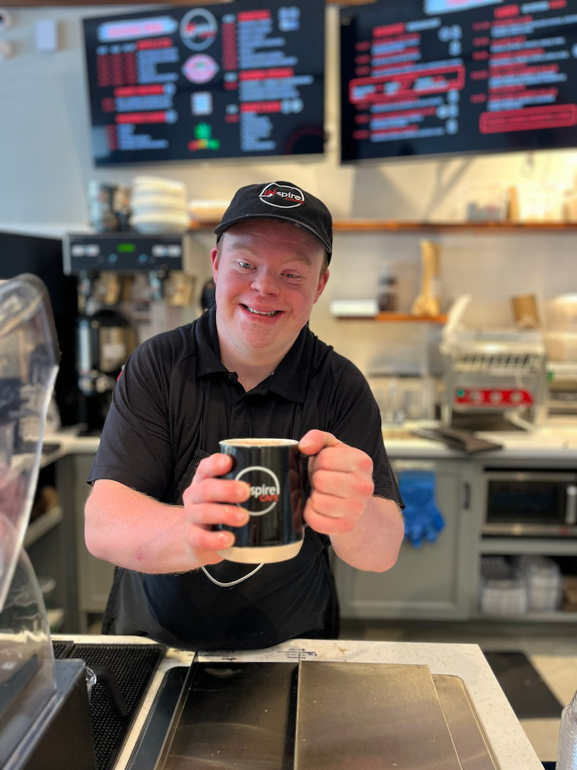 A team member at INspire Cafe serving a fresh coffee